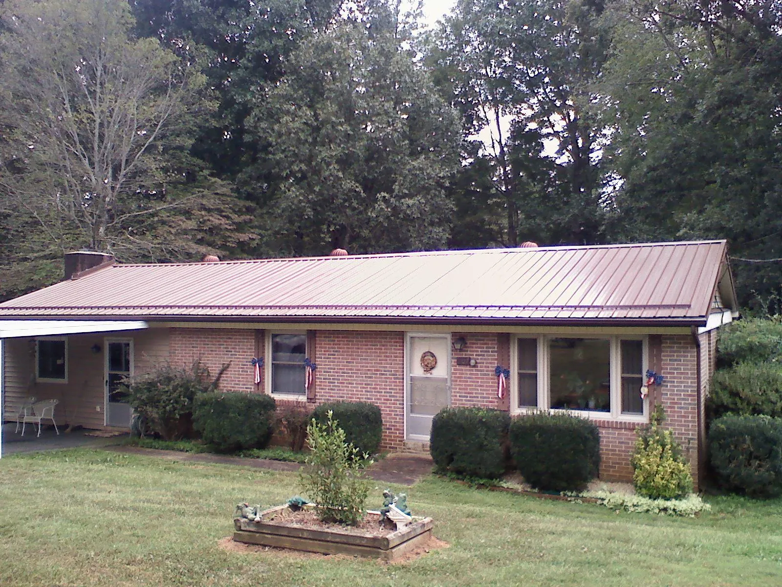 Bronze metal roof on a brick ranch home with a carport in Westover