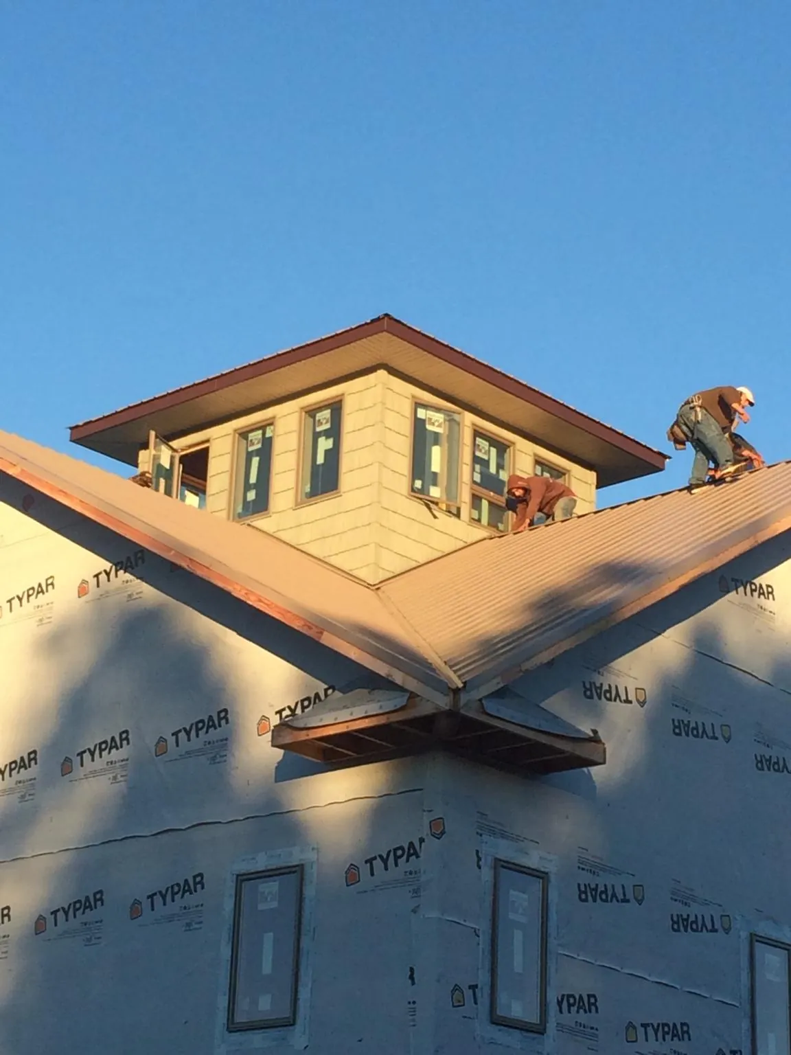 Roofers working around a rooftop cupola on a new metal roof at sunset — Roof Waterproofing in Westover by Roofing Brothers